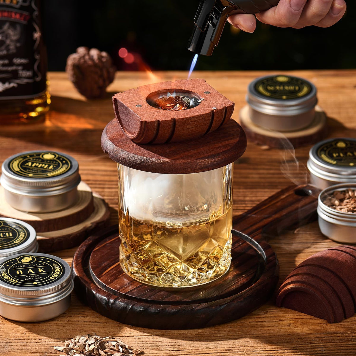 Cocktail smoker kit in use: the torch lights wood chips in the barrel smoker top on a glass of whiskey